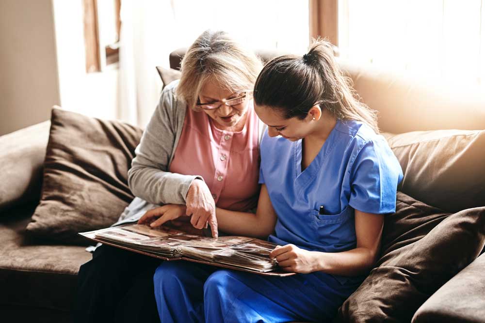 Caregiver and senior resident enjoying a nostalgic moment while looking through a photo album together.