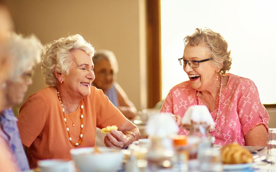 Happy in the home Two senior women happily engaging in conversation and laughter during breakfast at a senior community.